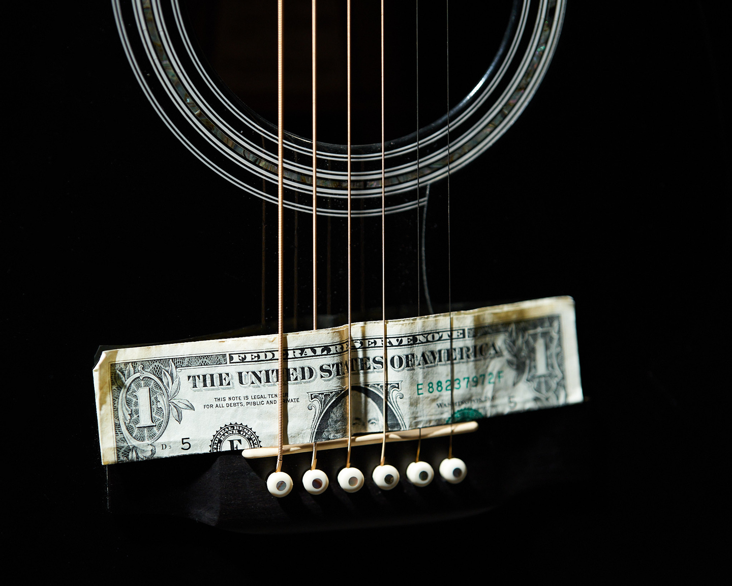 Photo of a dollar bill on the guitar bridge