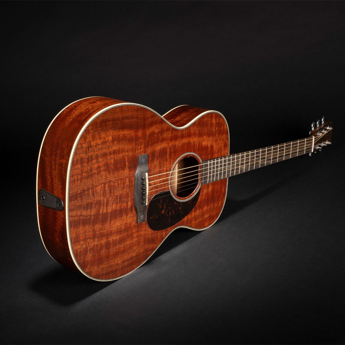 Acoustic guitar resting on a black background