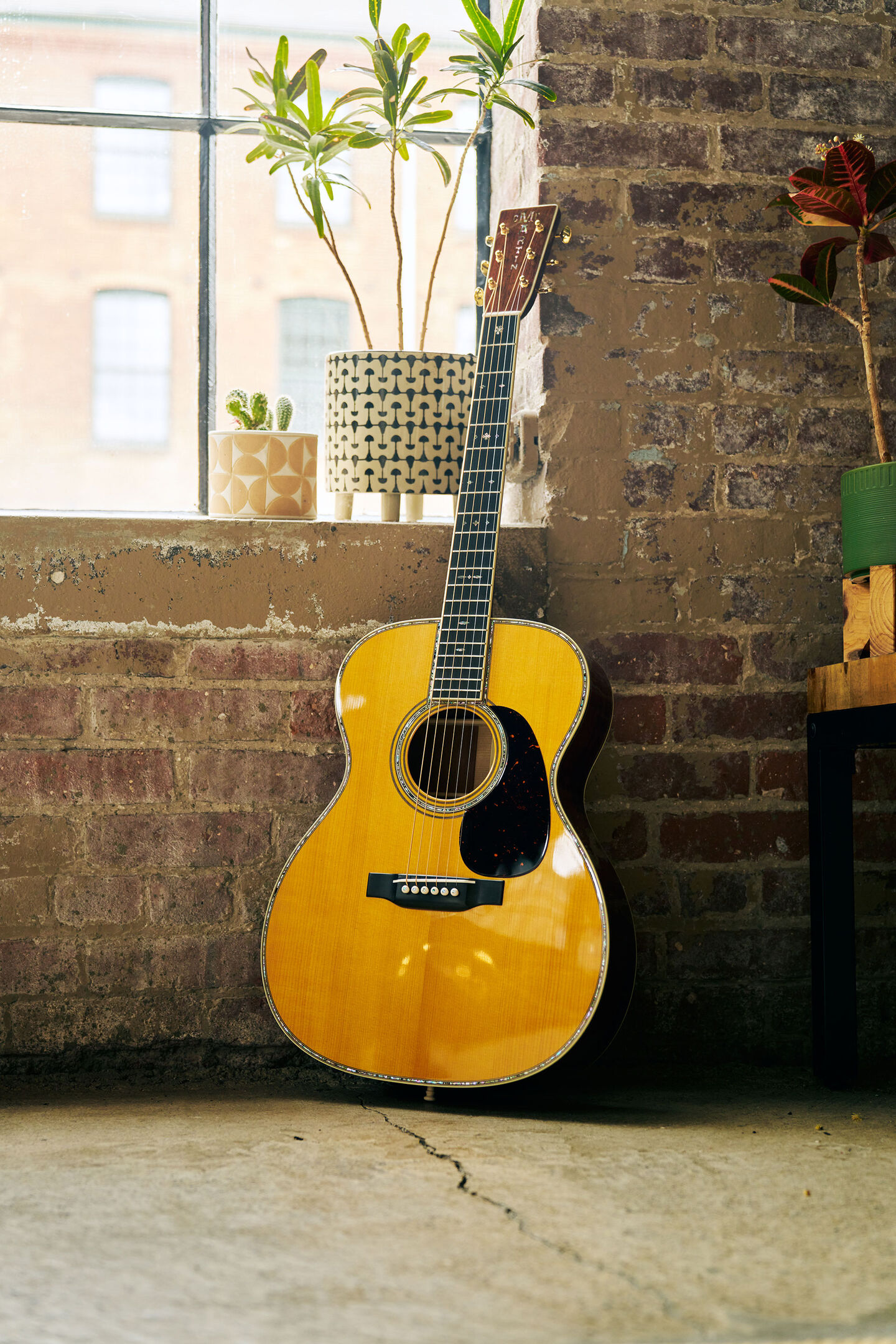 Acoustic guitar leaning against a brick wall