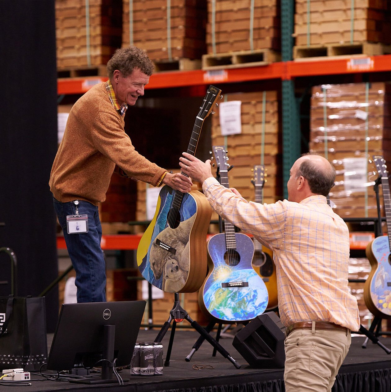 Two people handing a guitar to each other at the Martin Sustainability Summit