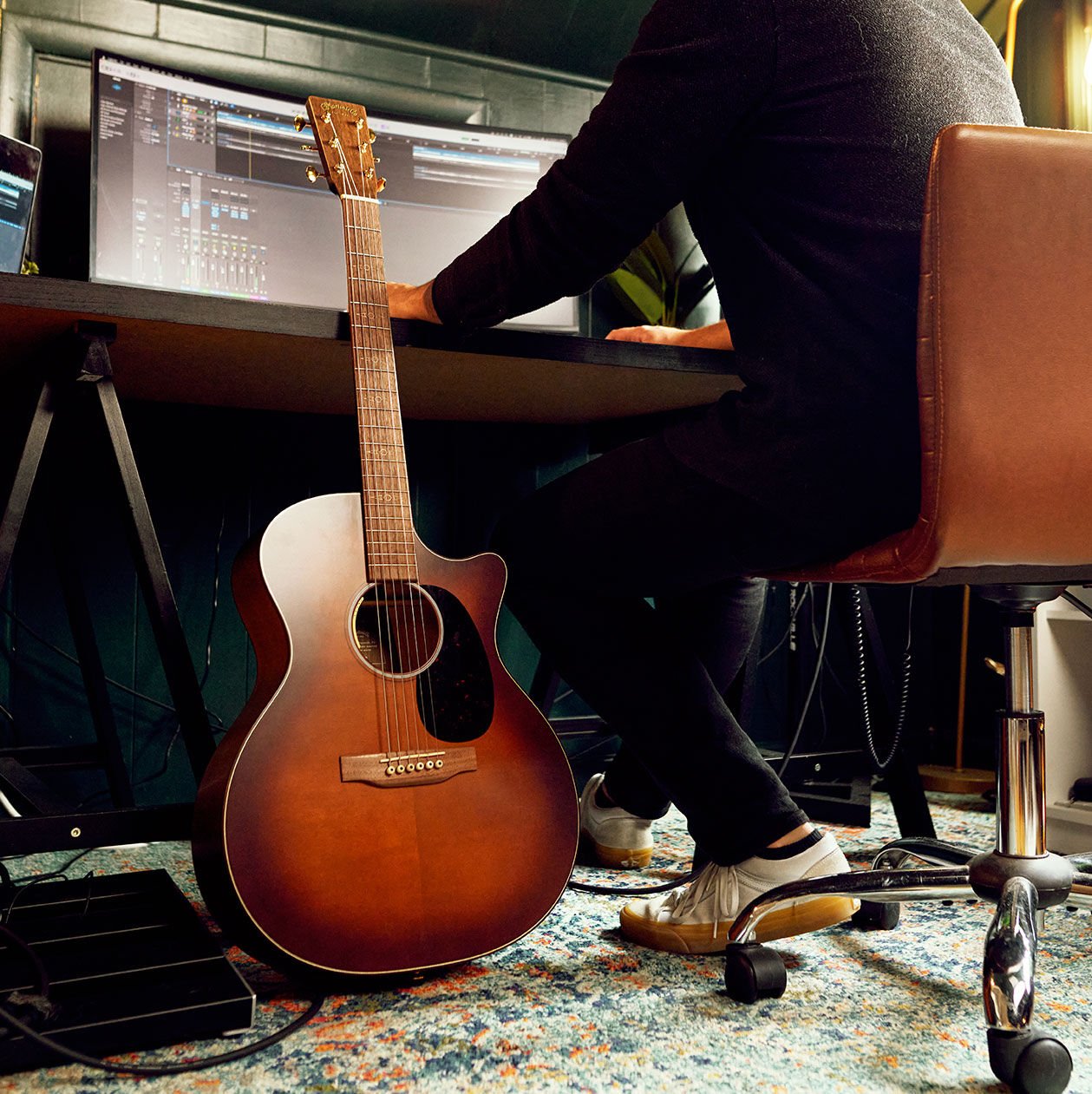 Person at desk with guitar leaning across it