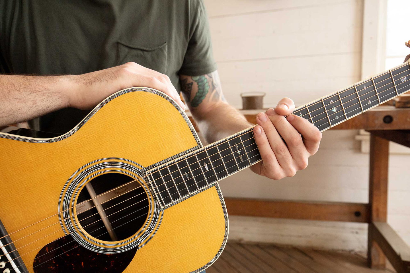 Closeup shot of a person holding a guitar. Their right hand is on the top of the guitar, with the left hand holding the neck