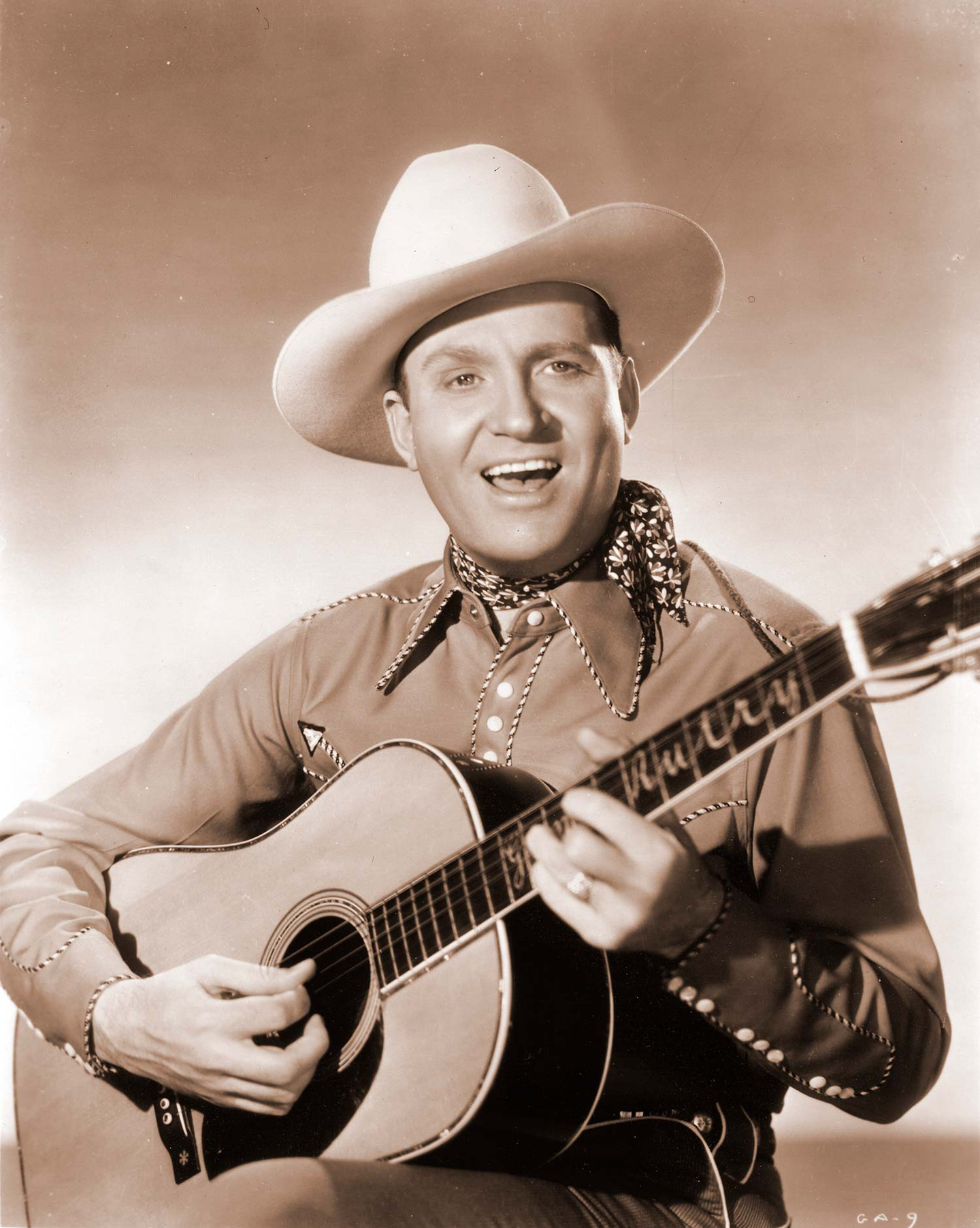 A sepia-toned photo of Gene Autry holding his Martin guitar A sepia-toned photo of Gene Autry holding his Martin guitar
