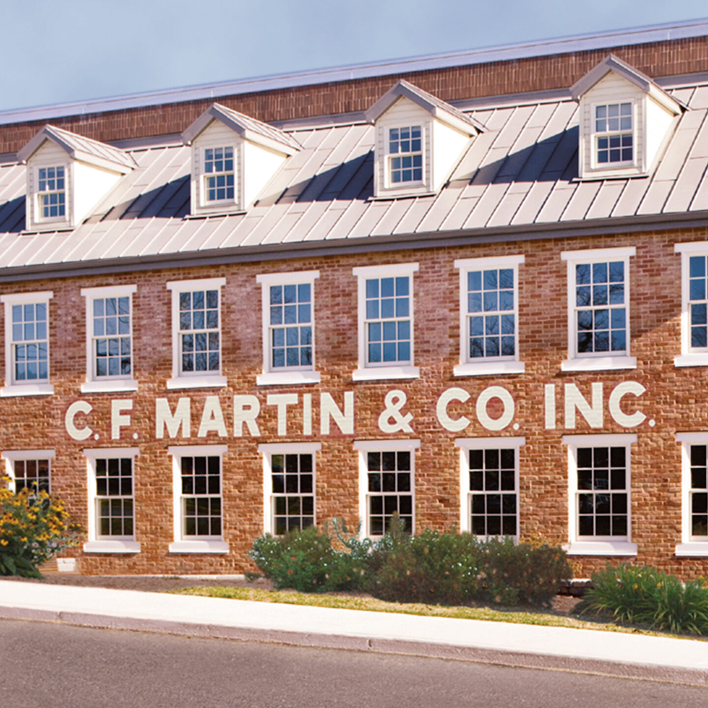 Looking at the Martin factory-an old red brick building with two rows of windows. Painted on the building in white paint is "C.F. MARTIN & CO INC"