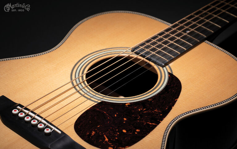 A close up shot of the body of an acoustic guitar lit up against a black background