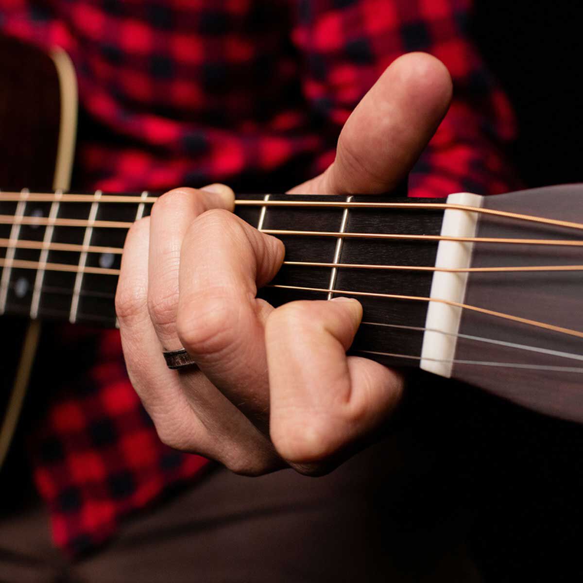 Close up shot of a person playing a C chord on an acoustic guitar