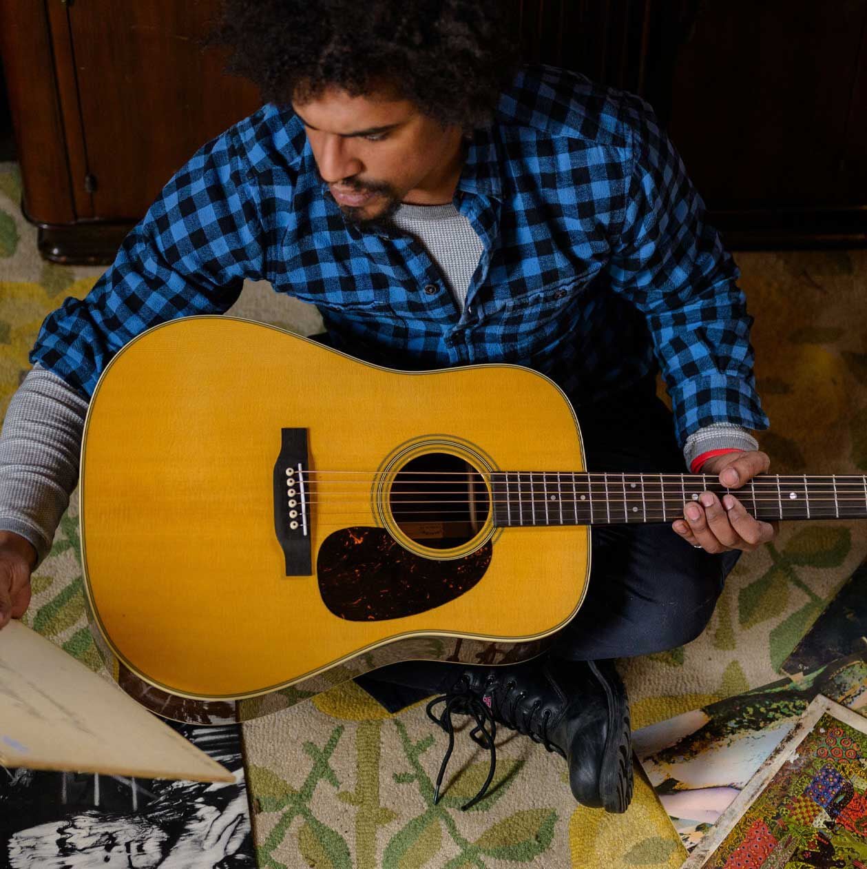 Man in a flannel shirt holding an acoustic guitar
