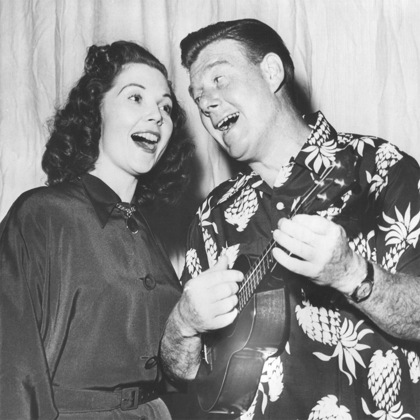 Black and white photo of a man and woman singing together while the man plays a ukulele Black and white photo of a man and woman singing together while the man plays a ukulele