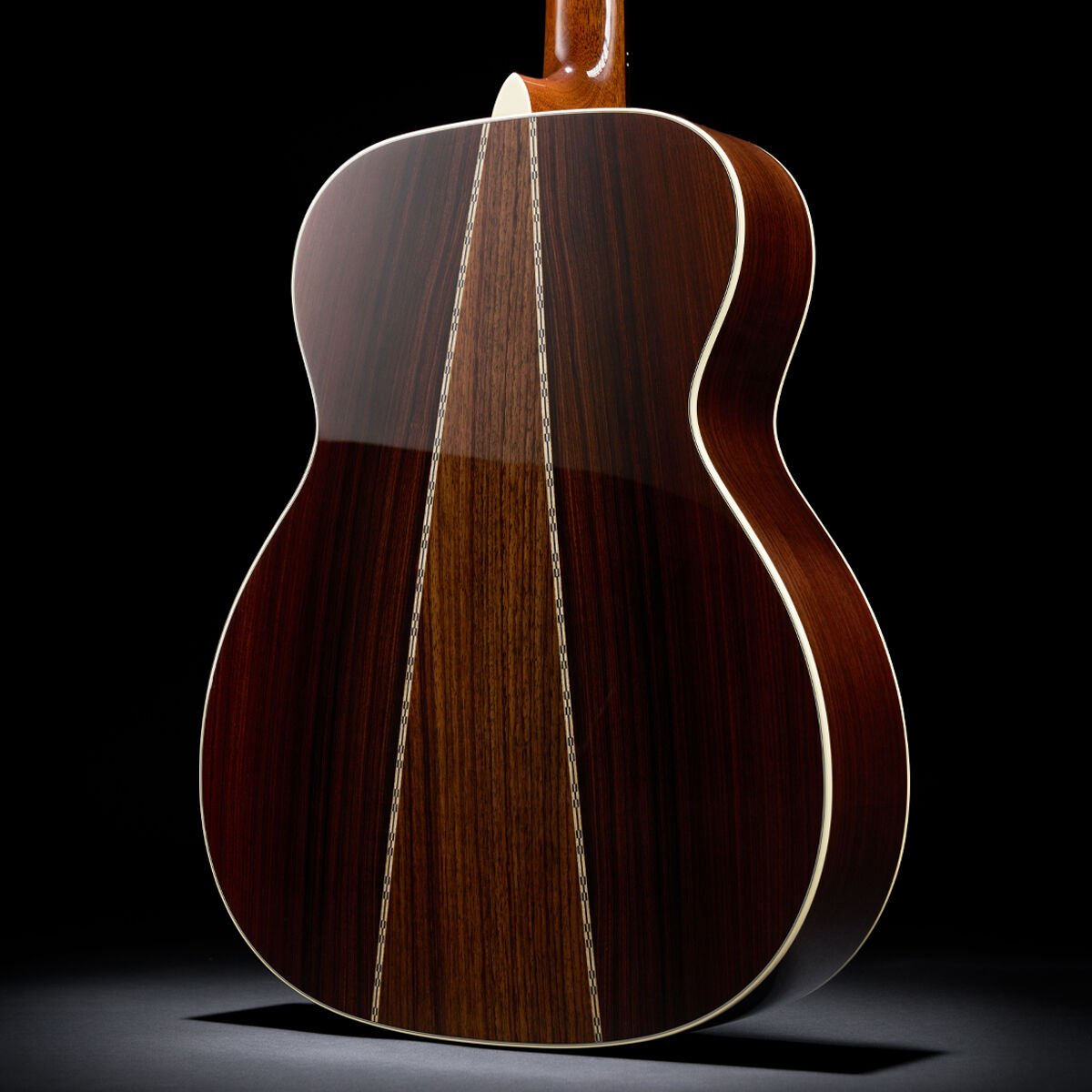 Detail shot of the back of an acoustic guitar, showing two different woods forming an upside down V from the neck