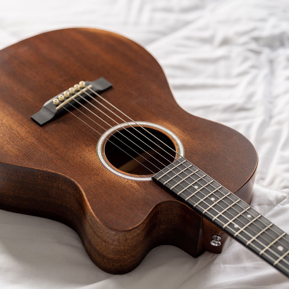 Acoustic guitar laying on a white cloth