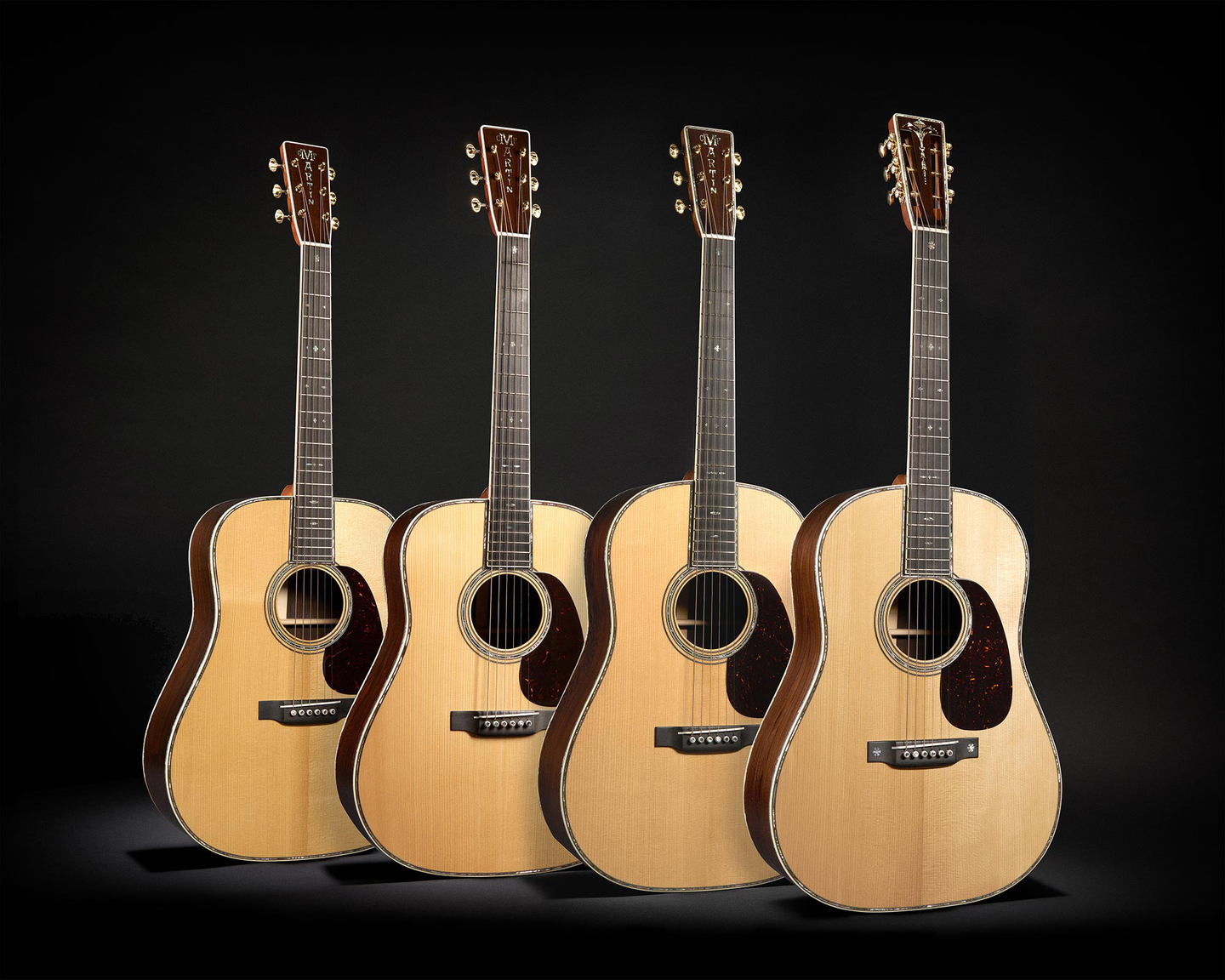 Four acoustic guitars on a black background