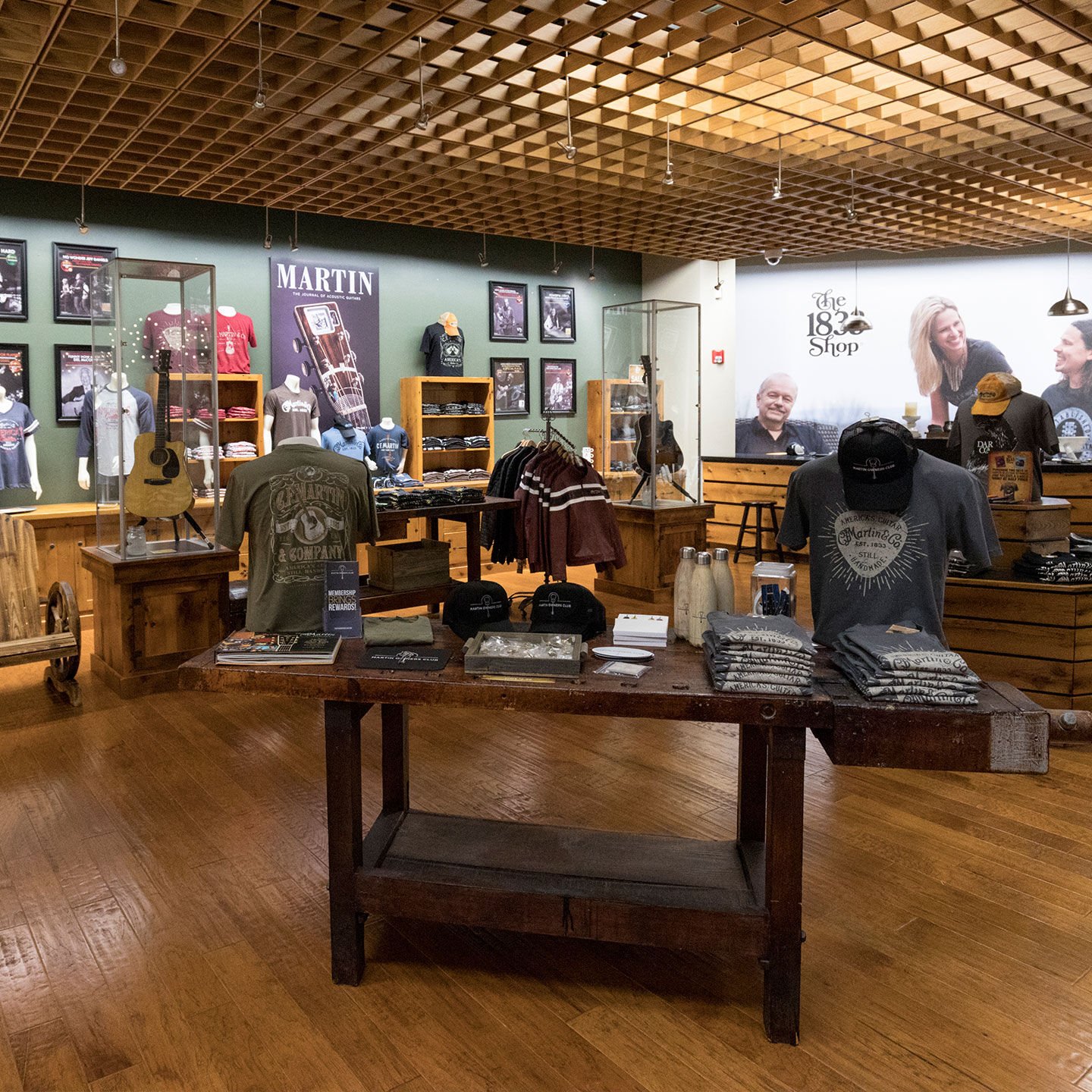 The inside of the Martin store. A latticed ceiling stands over a wooden floor and wooden tables holding merchandise such as books, t-shirts, trinkets, and guitars.