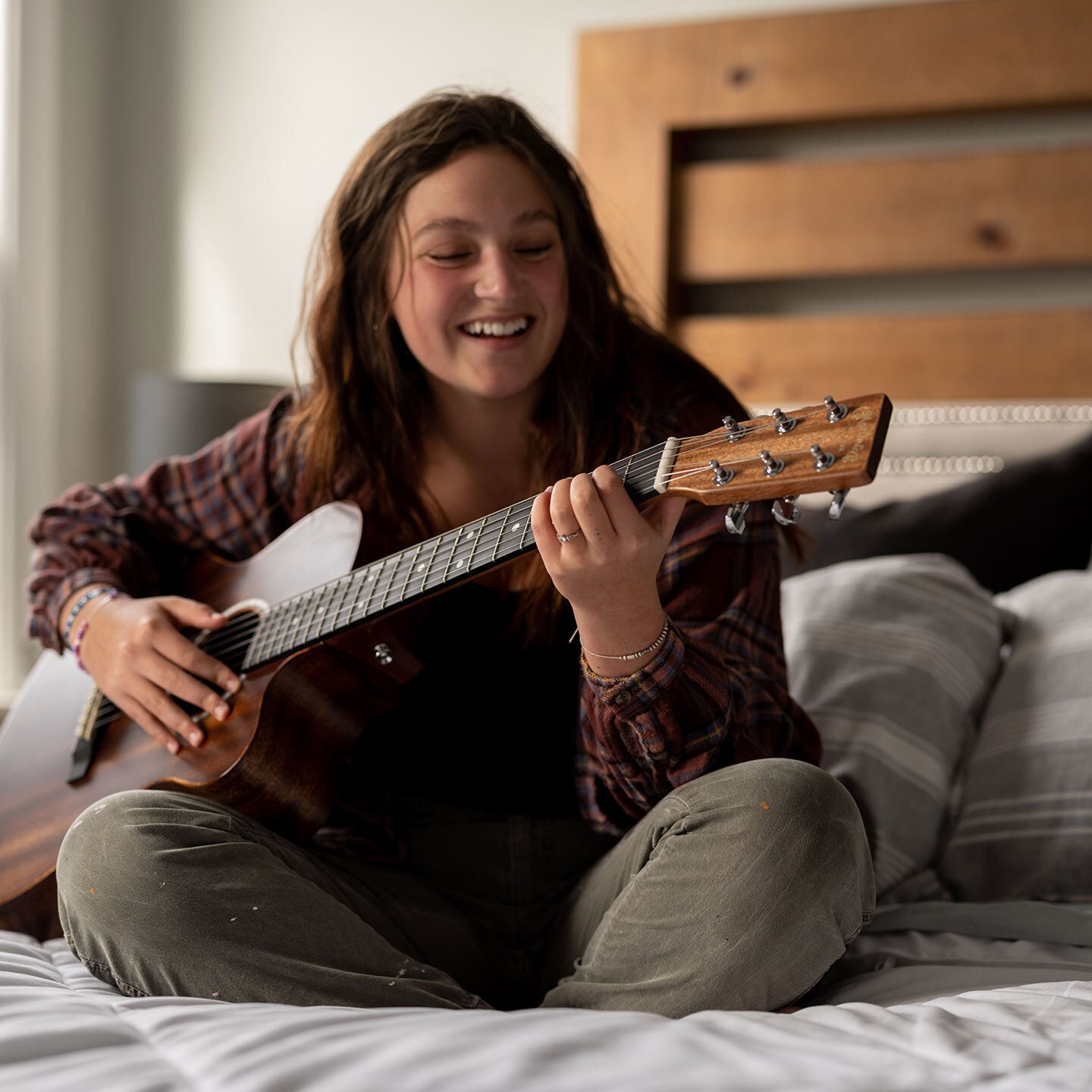 Woman playing guitar on bed