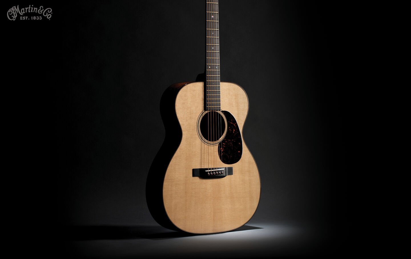 A photo of an acoustic guitar lit up dramatically against a black background