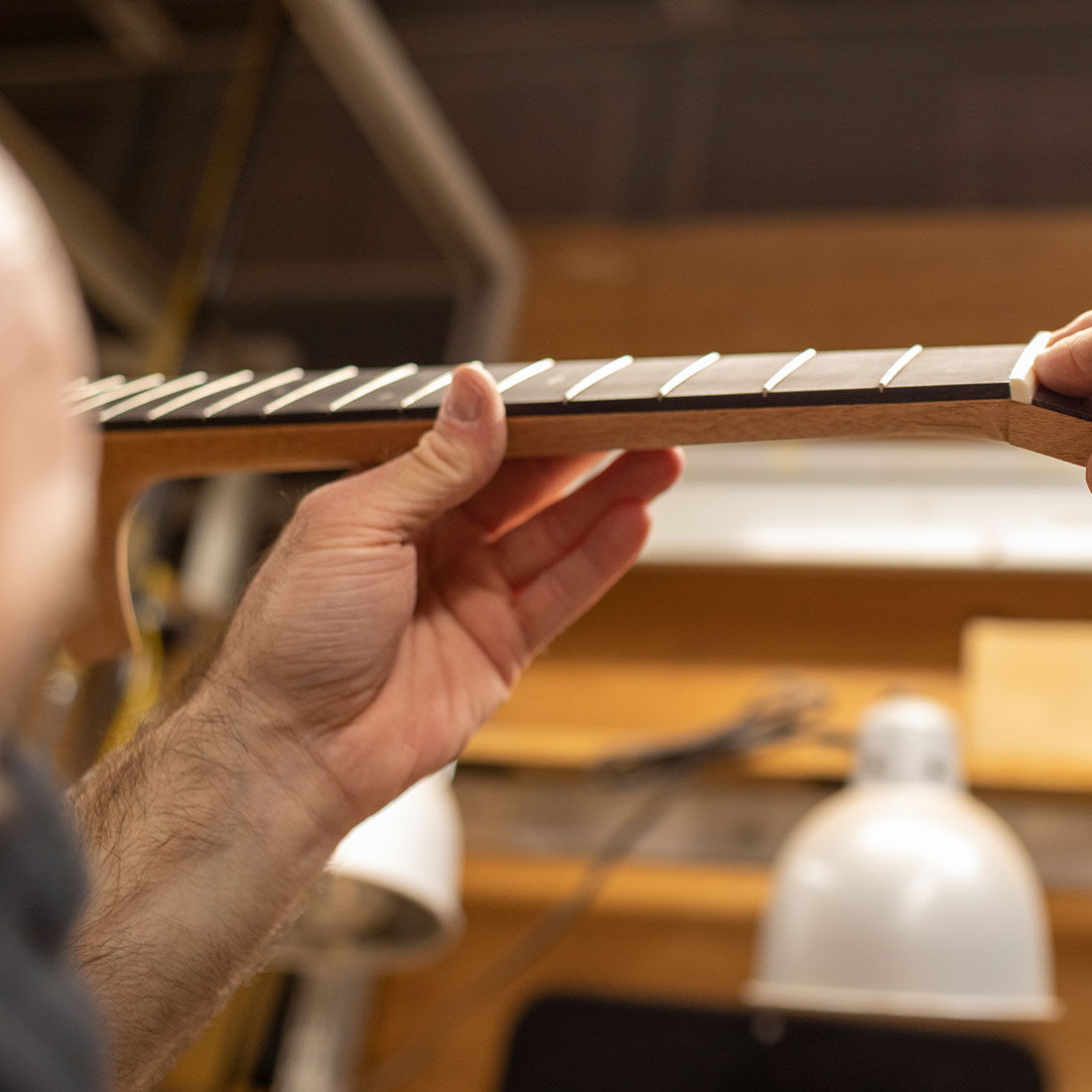 Person handling a guitar in a workshop.