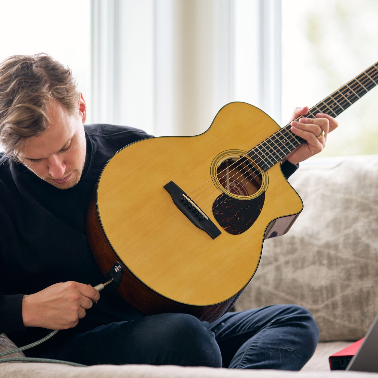 Person plugging in their acoustic-electric guitar