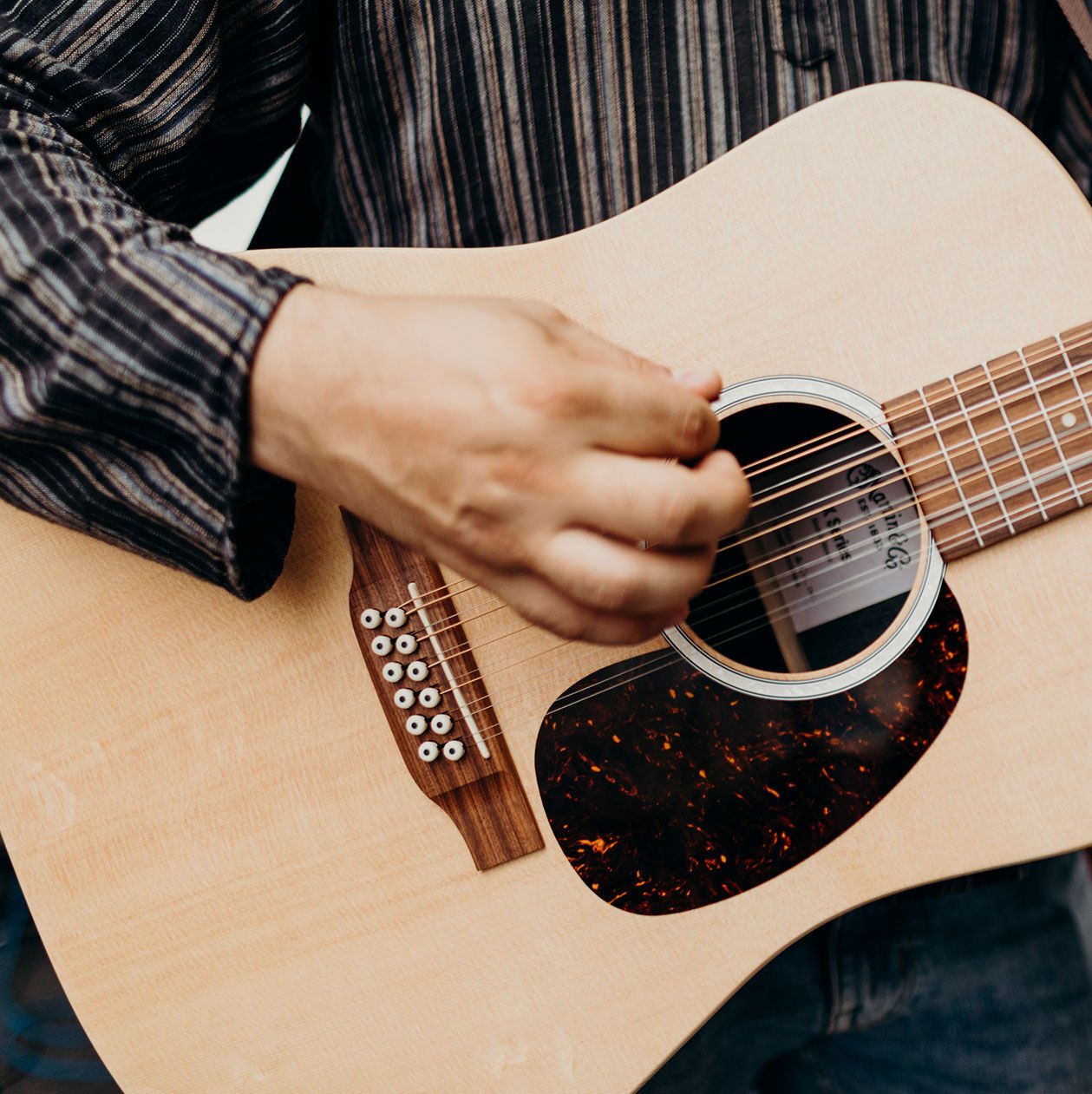 Person strumming a 12-string guitar Person strumming a 12-string guitar