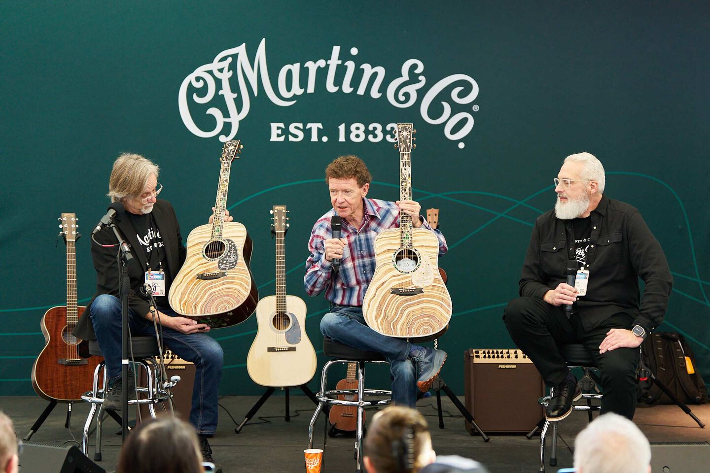 Three presenters in front of a Martin logo at the NAMM trade show