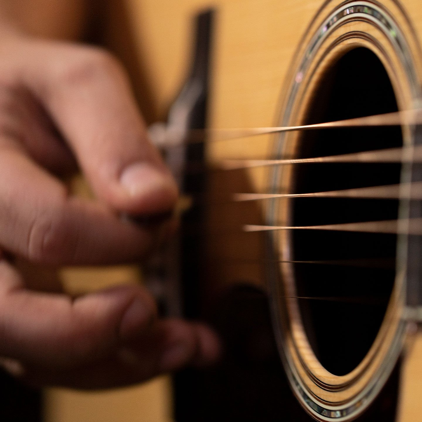 A closeup of a hand picking an acoustic guitar