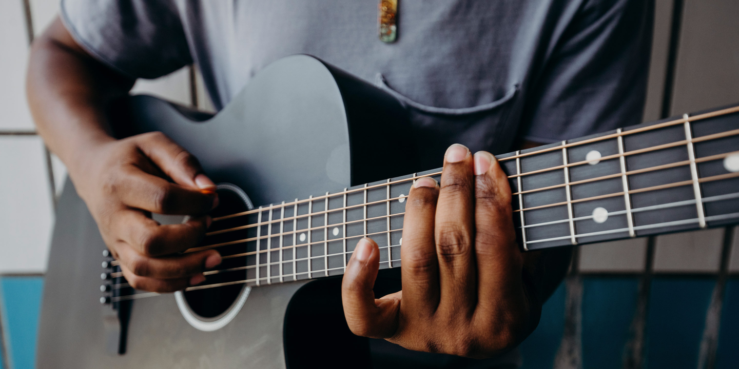 Person playing a black acoustic guitar