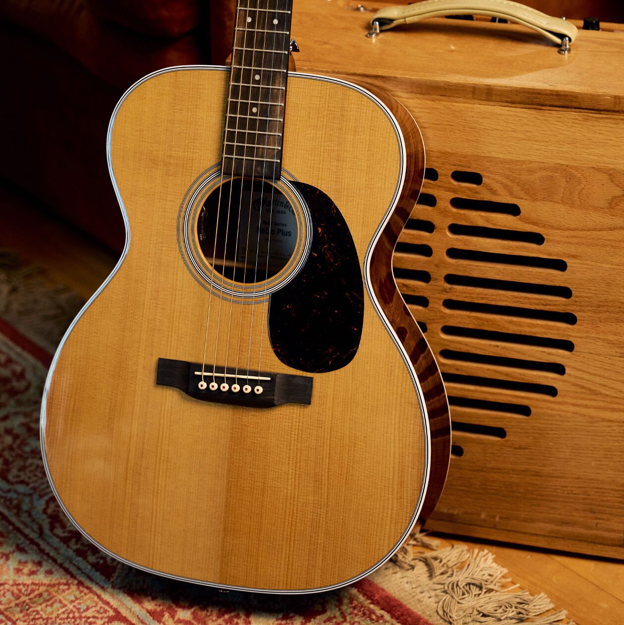 A Road Series acoustic guitar leaning up against a vintage wooden amplifier
