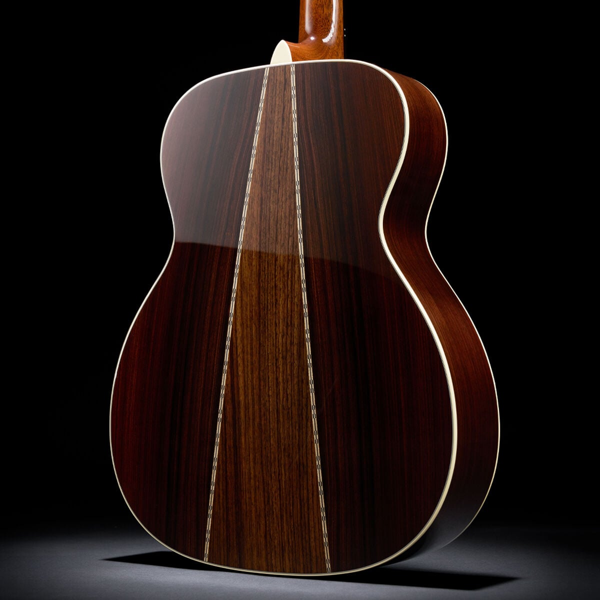Detail shot of the back of an acoustic guitar, showing two different woods forming an upside down V from the neck