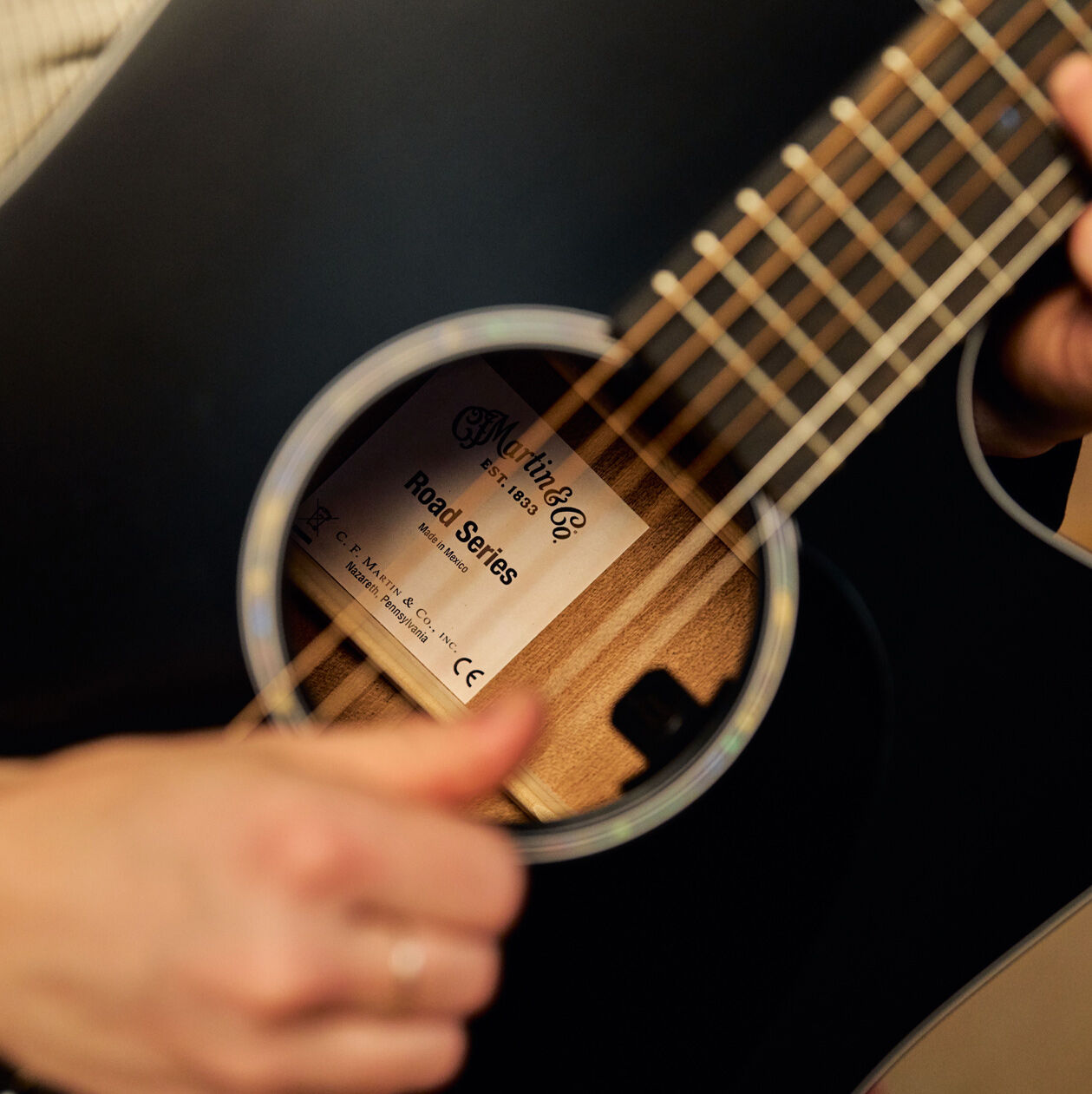 A person picking on a black cutaway acoustic guitar